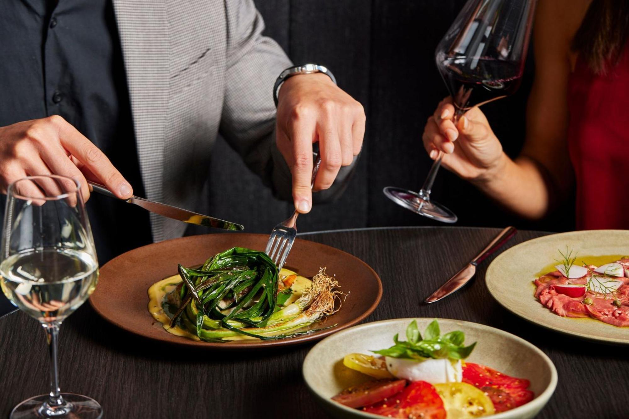 Melbourne Marriott Hotel Docklands Экстерьер фото A man using a knife and fork to cut into a meal